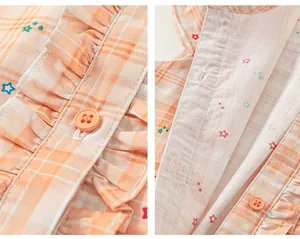 Detailed close-up of orange plaid fabric with star prints, ruffles, and matching buttons