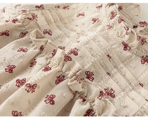 Detailed close-up of girls' cotton fabric with red bow print and textured bobble jacquard