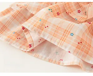 Close-up of orange plaid fabric featuring colorful star prints and neat hem stitching