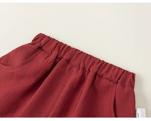 Detail view of red cotton-linen shorts showing elastic waistband and side pocket texture