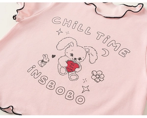 Detail eines rosa Baumwoll-T-Shirts mit schwarzen Rüschenkanten und süßem Hasen-Print