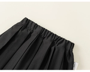 Détail de la ceinture élastique et de la texture plissée sur la jupe noire pour fille