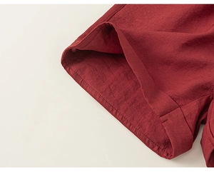 Detailed macro view of the dark red linen fabric texture and rolled hem stitching detail