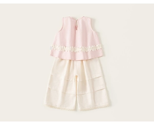 Détail du haut rose sans manches avec dentelle et pantalon large multicouche blanc cassé
