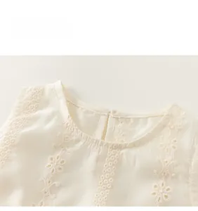 Detailansicht eines cremefarbenen Kindertops mit Blumenstickerei und Spitzenkragen