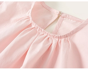 Détail du haut en coton rose montrant l'encolure ronde plissée et le petit bouton au dos
