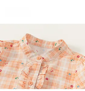 Close-up of orange plaid cotton dress with ruffled front and colorful star patterns