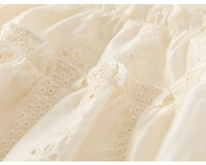 Detailaufnahme der Lochstickerei und Rüschenkanten an einem beigefarbenen Mädchen-Outfit