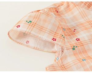 Detail of short sleeve cuff with orange gingham pattern and colorful star prints