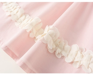Vue détaillée du tissu rose clair avec de la dentelle florale blanc crème en relief