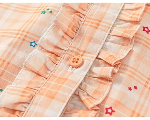 Detailed macro view of orange plaid dress with star prints and ruffle button placket