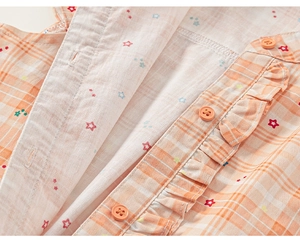 Detail of orange plaid fabric with colorful star prints and ruffle trim for girls