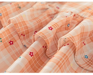 Close-up of lightweight orange plaid dress fabric with colorful star prints and soft texture
