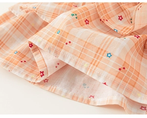 Detail of orange plaid fabric with small colorful star prints on a girl's summer dress