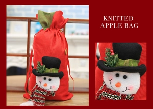 Close-up of a festive knitted Christmas gift bag featuring a 3D snowman with a red scarf