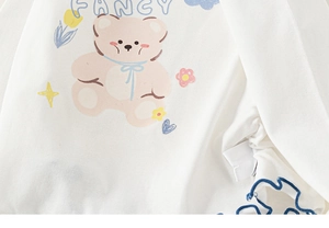 Detail of white cotton girls' top with pink bear print and blue ruffle hem edges
