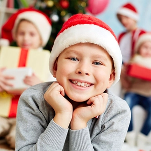 Classic red plush Christmas hat with white fur trim worn by a smiling boy in festive setting