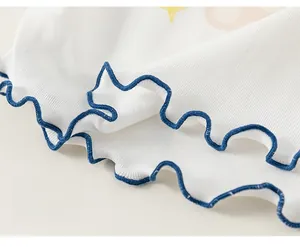 Detailed close-up of white ribbed fabric with blue lettuce hem stitching on kid's shirt