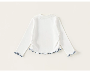 Detail of the white long-sleeve knit top featuring delicate navy blue lettuce trim edges
