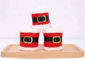 Three Santa Claus costume napkin rings with red fabric and black belt on a wooden tray