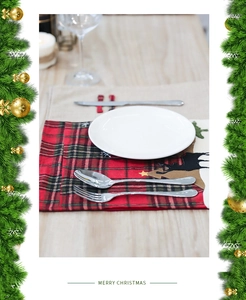 Détail d'un set de table de Noël à carreaux rouges et verts avec silhouette de renne brodée
