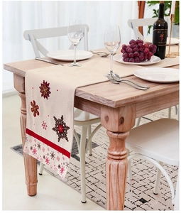 Close-up of Nordic beige linen table runner with red snowflake embroidery and tassels