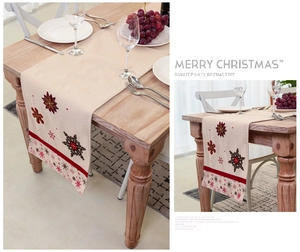 Detail of Nordic Christmas table runner with embroidered snowflakes on beige linen fabric