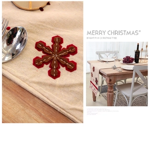 Detail of Nordic Christmas table runner showing beige linen texture and red snowflake applique