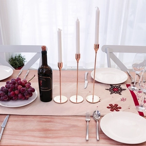 Three-piece rose gold metal candle holder set on elegant dining table with white candles