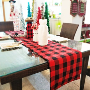 Detail of red and black buffalo plaid Christmas table runner with festive wine bottle covers