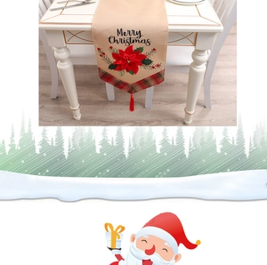 Close-up of Merry Christmas embroidery and red green plaid tassels on linen table runner