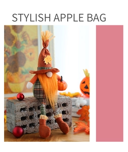 Detail of fall harvest gnome plush with maple leaf hat and orange pumpkin prop
