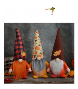 Three plush harvest gnomes with pumpkin hats standing on a wooden rustic surface