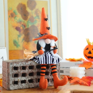 Gnomo di Halloween con cappello arancione a punta e scopa su un tavolo festivo accogliente