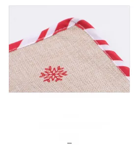 Macro shot of embroidered snowflake on rustic linen placemat with red striped border