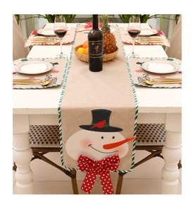 Detailed view of linen Christmas table runner with snowman embroidery and festive mats
