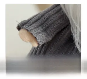 Makroaufnahme der grauen Strickstruktur und Filzhand eines Plüsch-Weihnachtsstern-Anhängers