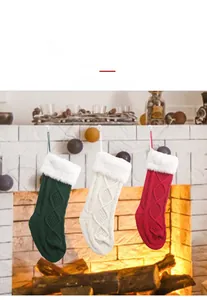 Drei gestrickte Weihnachtssocken in Rot, Weiß und Grün hängen an einem Kamin