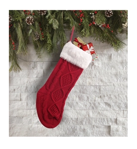 Makro-Detail des roten Zopfstrick-Weihnachtsstrumpfes mit weißem Kunstpelzbesatz und Deko