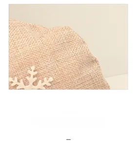 Macro shot of rustic flax Christmas gift bag featuring delicate white snowflake embroidery