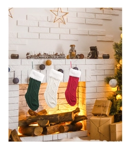 Nahaufnahme von drei gestrickten Weihnachtssocken am Kamin mit weißem Kunstpelzrand