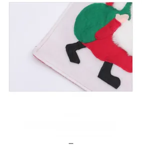 Close-up of festive red and green felt table runner with embroidered Santa legs and gift bag