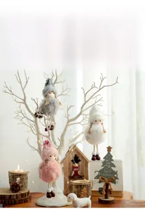Close-up of plush angel doll ornaments in pink and white hanging on Christmas branches