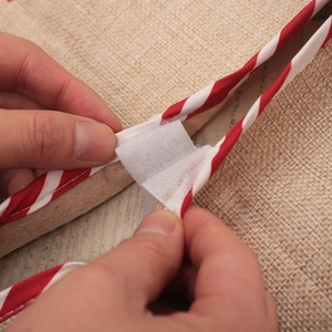 Christmas tree skirt with red white striped edges and velcro closure on burlap fabric