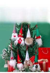 Close-up of colorful Christmas gnome ornaments with hats hanging on a green Xmas tree