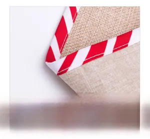 Macro detail of rustic burlap Christmas runner fabric with red and white candy cane piping