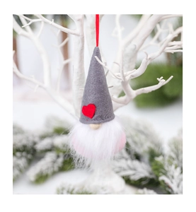 Close-up of Christmas gnome ornament with grey felt hat and red heart on festive branch