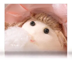 Macro shot of plush angel doll showing detailed bead eyes and soft curly hair texture