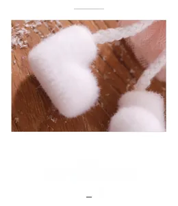 Close-up detail of plush white heart pompom and woven cord for Christmas angel doll