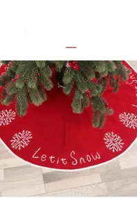Detail of red knitted Christmas tree skirt with white snowflakes and Let it Snow embroidery